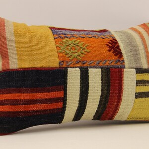 May include: A rectangular patchwork pillow with a variety of colorful stripes and patterns in shades of red, orange, yellow, blue, and white.