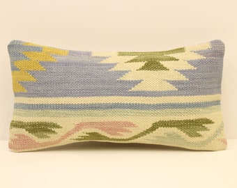 May include: A rectangular throw pillow with a woven pattern in shades of blue, green, yellow, and pink. The pillow has a light beige background.