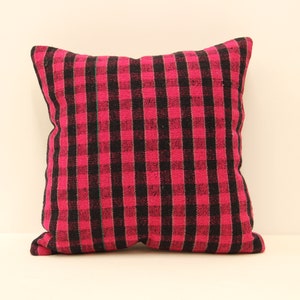 May include: A pink and black checkered throw pillow with a green stripe down the center.