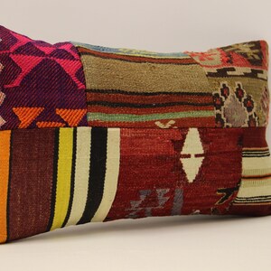 May include: A rectangular patchwork cushion with a variety of colours and patterns, including red, orange, yellow, green, blue, purple, and brown. The cushion is made of woven fabric and has a fringed edge.