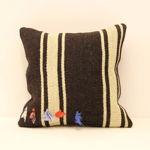 May include: A brown and white striped throw pillow with colorful fabric accents. The pillow is made of a woven fabric and has a soft, comfortable texture.