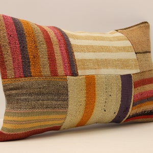 May include: A rectangular cushion with a patchwork design. The cushion is made of different coloured fabrics, including red, orange, brown, and white. The fabric is woven with stripes.