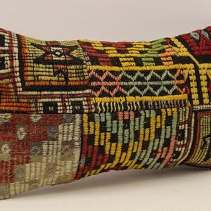 May include: A colorful rectangular pillow with a patchwork design featuring geometric patterns in shades of red, yellow, green, blue, and black.