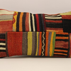 Può includere: Un cuscino rettangolare con un design a patchwork. Il cuscino è realizzato con tessuti di diversi colori, tra cui rosso, arancione, giallo, verde, blu e nero. Il tessuto è intrecciato a righe.
