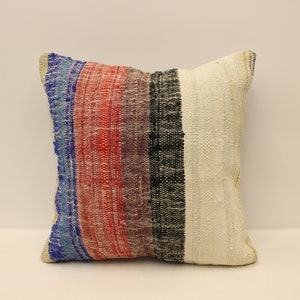 Puede incluir: Una almohada de tiro blanca, roja, azul, negra y morada con rayas y textura tejida.