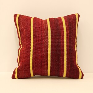May include: Red and yellow striped throw pillow. The pillow is made of a woven fabric with a textured surface.