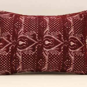 May include: A burgundy throw pillow with a white floral pattern. The pillow is made of a soft, textured fabric.