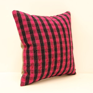 May include: A pink and black striped throw pillow with a subtle green accent. The pillow is made of a woven fabric and has a slightly textured surface.