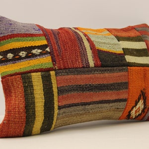 May include: A colourful patchwork cushion with a variety of stripes and patterns in shades of red, orange, yellow, green, blue, and brown.