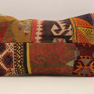 May include: A rectangular pillow with a patchwork design. The pillow is made of different fabrics with various colors and patterns, including red, orange, yellow, green, blue, and brown. The pillow is perfect for adding a touch of bohemian style to any room.