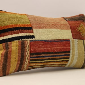 May include: A rectangular patchwork cushion with a variety of colourful stripes and patterns in shades of brown, orange, red, and beige.