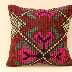 May include: A red, green, pink, blue, and yellow patterned throw pillow with a woven texture.