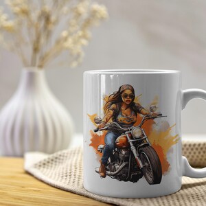 K&ouml;nnte beinhalten: Wei&szlig;e Keramiktasse mit einer bunten Illustration einer Frau, die ein Motorrad f&auml;hrt. Die Frau tr&auml;gt eine Sonnenbrille und ein Bandana. Der Hintergrund ist ein Aquarell-Design in Orange- und Gelbt&ouml;nen.