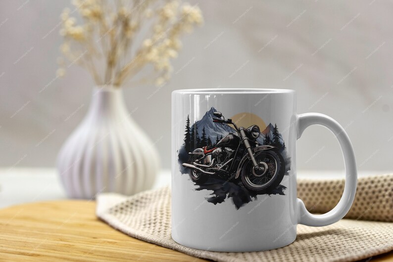 May include: White ceramic mug featuring a black and white illustration of a motorcycle in a mountain landscape. The motorcycle has a red seat and a black and white colour scheme.