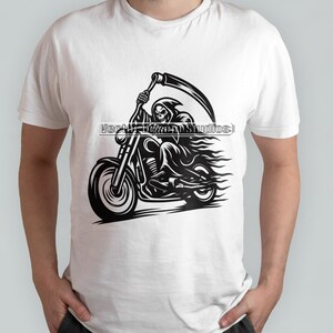 Może przedstawiać: Biała koszulka z czarną grafiką przedstawiającą Grim Reapera na motocyklu, trzymającego kosę. Projekt zawiera płomienie i tekst "Vector Team Studios".
