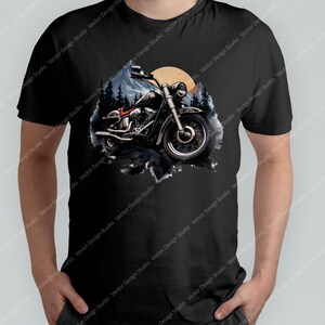 May include: A black t-shirt featuring a graphic of a motorcycle riding through a forest with a sunset in the background.