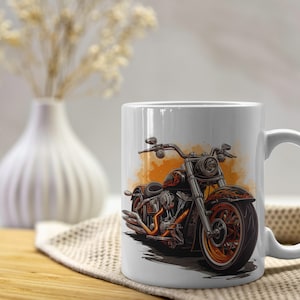 May include: White ceramic mug featuring a detailed illustration of a black and orange motorcycle. The motorcycle design has orange accents and is set against an orange watercolor-style background. The mug has a curved handle and is placed on a wooden surface.
