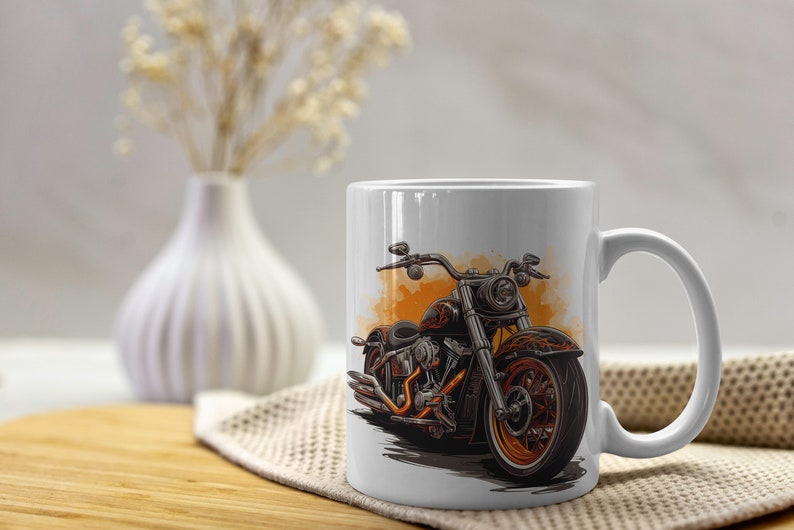 May include: White ceramic mug featuring a detailed illustration of a black and orange motorcycle. The motorcycle design has orange accents and is set against an orange watercolor-style background. The mug has a curved handle and is placed on a wooden surface.