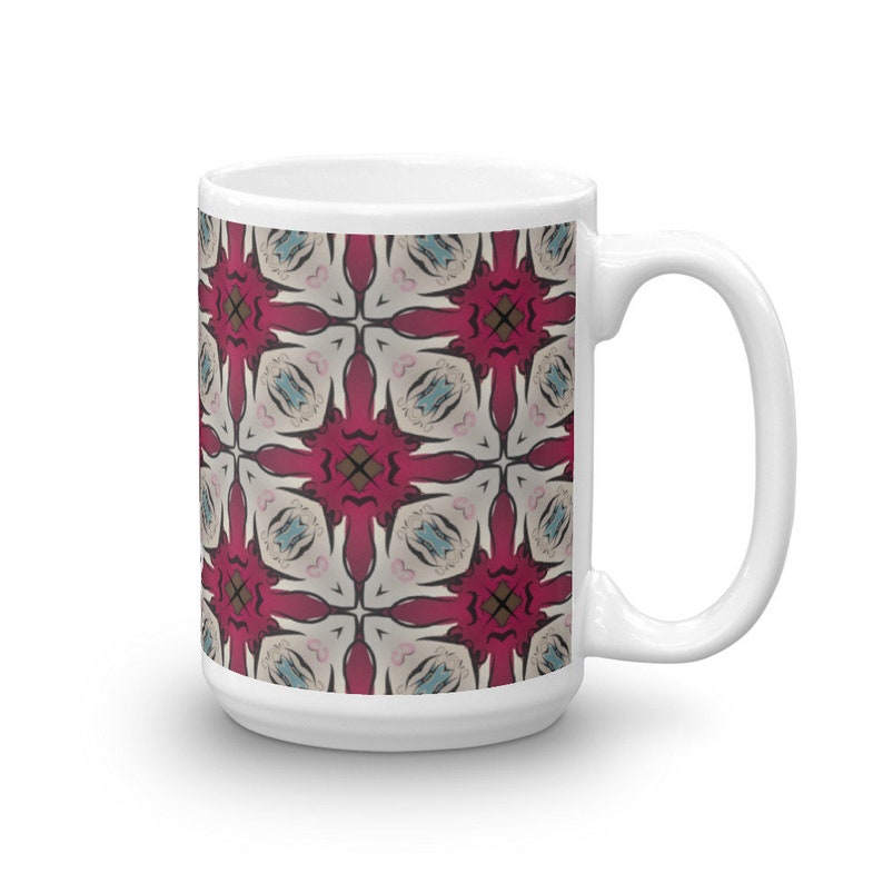 May include: White ceramic mug with a geometric pattern in shades of red, pink, and blue. The pattern is a repeating design of stylized flowers.