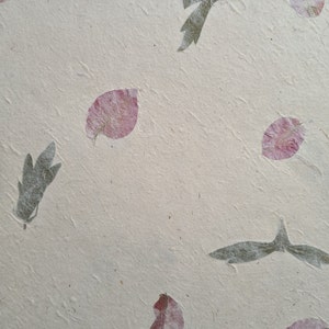 May include: A sheet of handmade paper with pressed pink flower petals and green leaves. The paper has a textured surface.