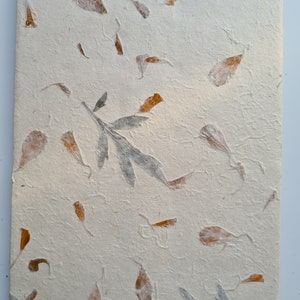 May include: A white textured paper with brown and gray pressed leaves and flowers. The paper has a handmade look and feel.