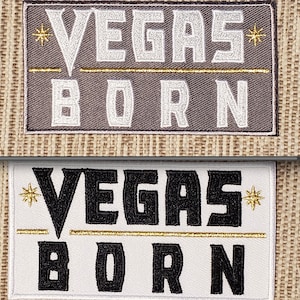 May include: Two embroidered patches with the text "Vegas Born" in white and black lettering on a gray and white background. The patches have a gold star and a gold line.