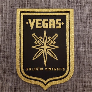 Könnte beinhalten: Ein gestickter Aufnäher in Schwarz und Gold mit den Worten "Vegas Golden Knights" und einem Stern mit gekreuzten Schwertern.