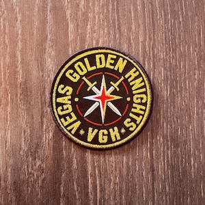 May include: A circular patch with the words "VEGAS GOLDEN KNIGHTS" in gold. The central design is a starburst with a red centre and white points, and two crossed swords. The letters "VGH" are also present.