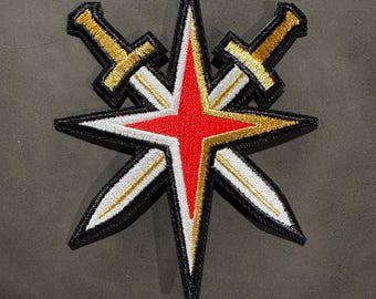 Peut inclure: Un patch brodé noir, blanc, or et rouge représentant une étoile avec deux épées croisées. L'étoile a un centre rouge et des pointes blanches. Les épées sont dorées avec des accents blancs.