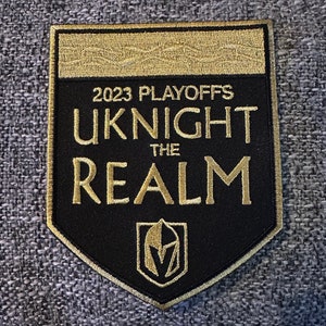 May include: A black and gold embroidered patch with the text "2023 Playoffs UKNIGHT THE REALM" and a gold knight's helmet logo.