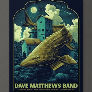 May include: A concert poster for Dave Matthews Band, featuring a stylized illustration of a large fish jumping over a small town with a full moon in the background. The text reads "Dave Matthews Band" and "June 26, 2024 - Pine Knob Music Theatre - Clarkston, MI".