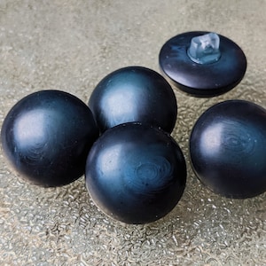 Op de afbeelding: Vijf donkerblauwe ronde knoppen met een lichte glans. De knoppen hebben een glad, licht getextureerd oppervlak.