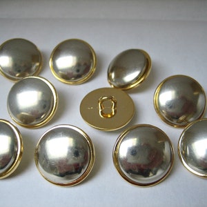 Peut inclure: Dix boutons ronds argentés et dorés avec un centre surélevé. Les boutons ont une finition lisse et brillante.