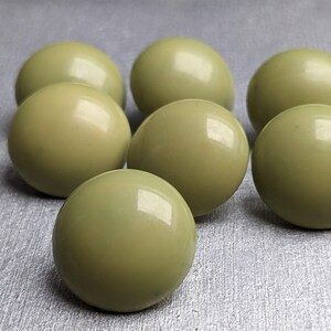 以下が含まれることがあります： 丸い緑色の光沢のあるボタンが7つあります。