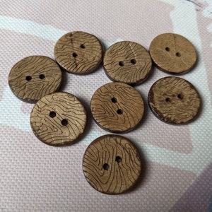 Könnte beinhalten: Acht braune Holzknöpfe mit Holzmaserung und jeweils zwei Löchern.