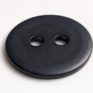 Könnte beinhalten: Ein schwarzer Gummiknopf mit zwei Löchern in der Mitte.