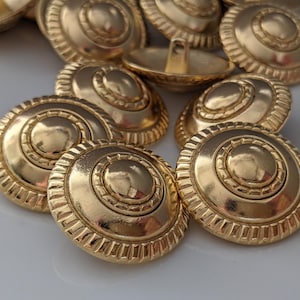 May include: A collection of gold-colored buttons with a decorative, circular design. The buttons have a raised center and a detailed, ridged edge. The image includes the text "#01" in the lower left corner.