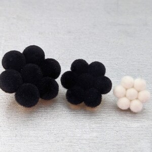 May include: Three black velvet flower-shaped embellishments with a white velvet flower-shaped embellishment.