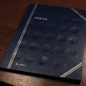 May include: A blue leather-bound book with a silver border and the word "CENTS" embossed on the front cover. The book is labeled "No. 9041".
