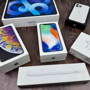 以下が含まれることがあります： iPad Air、iPhone、AirPods、Apple Pencilなど、Apple製品の詰め合わせが、オリジナルのパッケージに入って展示されています。箱は白いAppleのロゴ入りで、一部の箱の中にはデバイスが見えます。