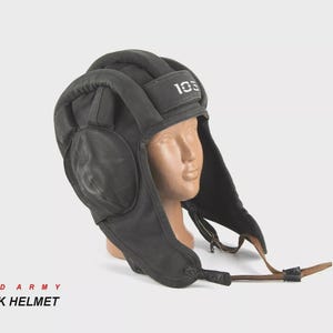 Peut inclure: Casque de char noir avec cache-oreilles et jugulaire. Le casque porte le numéro "103" imprimé en blanc sur le dessus. Le texte "RED ARMY TANK HELMET" est imprimé en rouge et noir en bas de l'image.