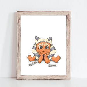 May include: A framed print featuring a cartoon illustration of a character with orange skin, a headpiece, and blue and white markings. The character is sitting with hands under the chin, with two silver objects in front.