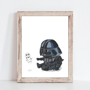 May include: A framed print featuring a cartoon illustration of a baby Darth Vader in a black and blue suit, helmet, and a small Stormtrooper. The artwork is set against a white background, with a light brown wooden frame.