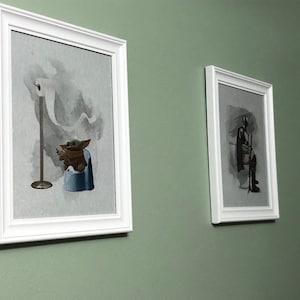 May include: Two framed prints on a green wall. The print on the left shows a cartoon character sitting on a toilet with a roll of toilet paper hanging above. The print on the right shows a cartoon character sitting on a toilet with a lightsaber.