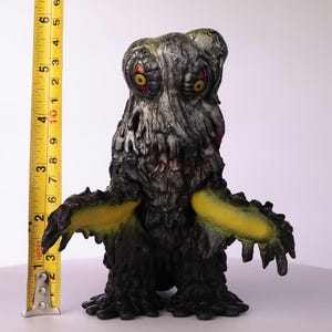 Puede incluir: Una taza de cer&aacute;mica blanca con un asa negra y el texto "But First, Coffee" en negrita negra. La taza est&aacute; sobre una superficie de madera. La taza mide aproximadamente 10 cm de alto.