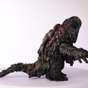 Puede incluir: Figura detallada, pintada a mano, de una criatura con un cuerpo oscuro y texturizado. La figura tiene una postura encorvada, con una larga cola y brazos extendidos. Los acentos rojos y verdes a&ntilde;aden color.