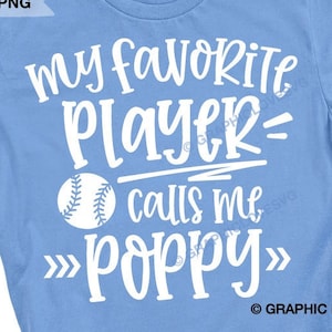 Pode incluir: Uma camiseta azul claro com texto branco que diz "Meu jogador favorito me chama de papai" com um gr&aacute;fico de beisebol.