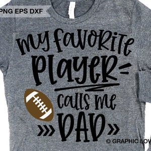 May include: A gray t-shirt with black text that reads "My favorite player calls me DAD" with a brown football graphic. The text is surrounded by arrows pointing inwards.