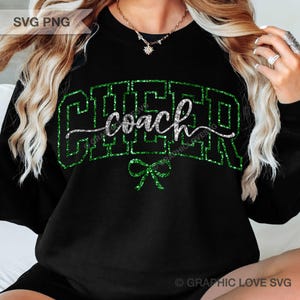 May include: Black sweatshirt with the words "CHEER coach" in green glitter lettering. A green glitter bow is below the word "coach". The sweatshirt is a crew neck style.