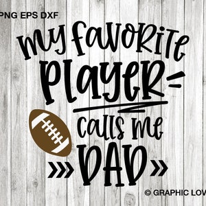 May include: Black and white graphic text on a woodgrain background that reads "my favorite player calls me DAD" with a brown football graphic to the left of the text.